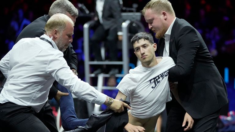 La seguridad se lleva a un hombre después de prenderle fuego en la mano durante una protesta en un partido Diego Schwartzman del Team World contra Stefanos Tsitsipas del Team Europe el primer día del torneo de tenis Laver Cup en el O2 de Londres. , viernes 23 de septiembre de 2022. (Foto AP/Kin Cheung)