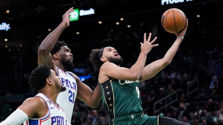 Boston Celtics guard Derrick White (9) drives past Philadelphia 76ers center Joel Embiid (21) and forward Tobias Harris (12) during the first half of an NBA basketball game Tuesday, Oct. 18, 2022, in Boston.