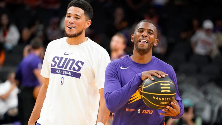 Phoenix Suns guards Devin Booker, left, and Chris Paul, right, share a laugh before the first half of an NBA preseason basketball game against the Adelaide 36ers