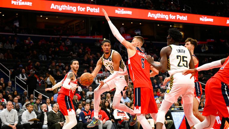 Indiana Pacers guard Tyrese Haliburton (0) leaps between Washington Wizards center Kristaps Porzingis (6) and forward Kyle Kuzma, left, during the second half of an NBA basketball game, Friday, Oct. 28, 2022, in Washington. The Pacers won 127-117. (AP Photo/Nick Wass)