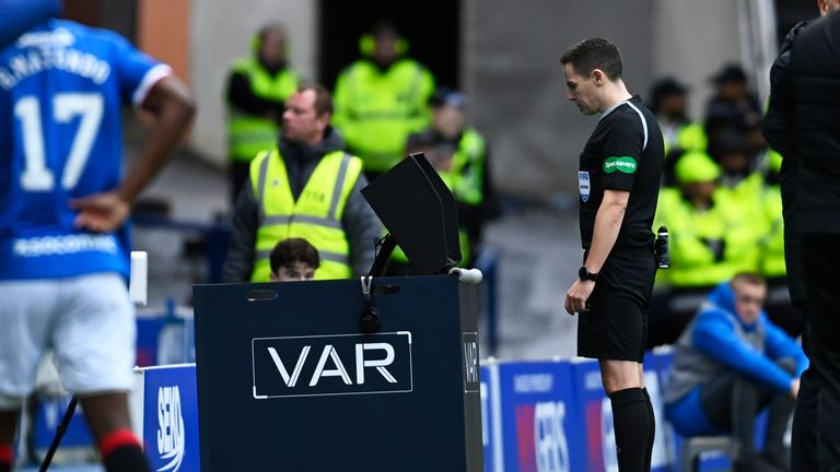 Referee David Munro checks VAR before sending off Morgan Boyes