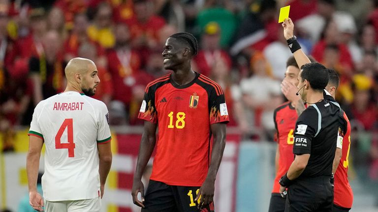 Referee Cesar Ramos shows a yellow card to Belgium's Amadou Onana