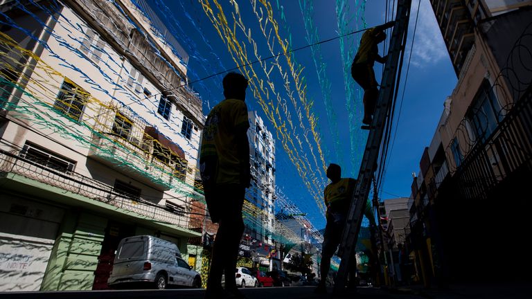 Residents decorate a street with green and yellow streamers in Rio de Janeiro