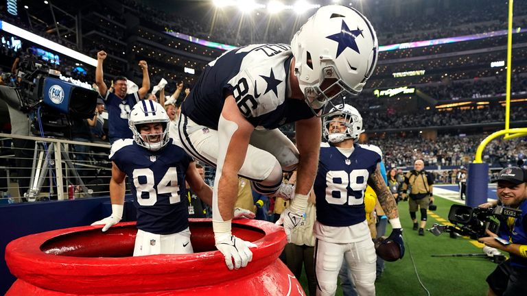 Dallas Cowboys' Dalton Schultz (86) jumps out of a Salvation Army kettle while celebrating Peyton Hendershot's (89) touchdown along with Sean McKeon (84) against the New York Giants