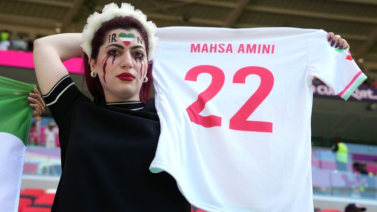 An Iran fan holding a shirt in memory of Mahsa Amini