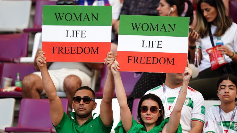 Iran fans in the stands hold up signs reading "Woman Life Freedom" ahead the match against England