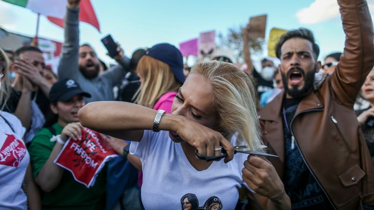 Seorang wanita memotong rambutnya saat protes terhadap kematian Iran Mahsa Amini, di Istanbul (pic: AP)