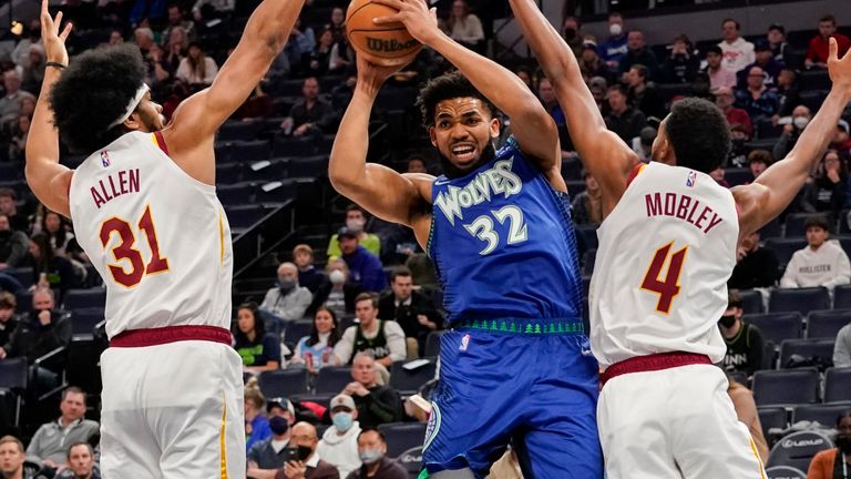 Karl-Anthony Towns of the Minnesota Timberwolves tries to weave a way between Cleveland Cavaliers defenders Jarrett Allen and Evan Mobley