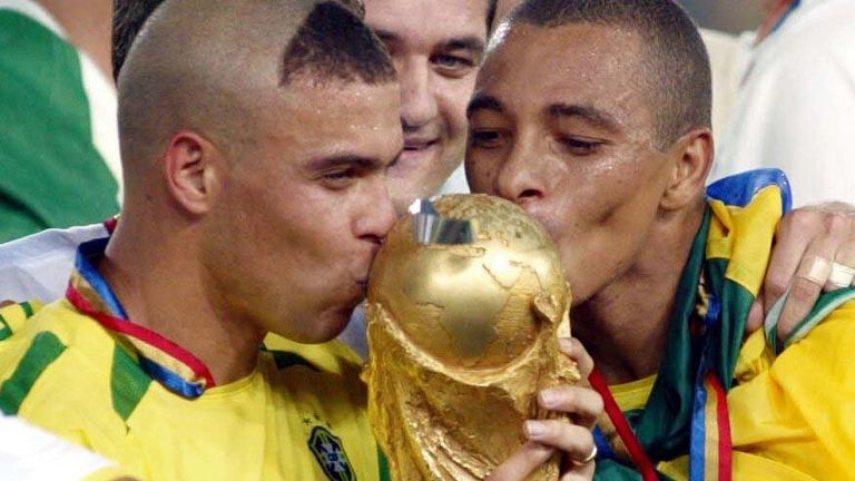 Ronaldo and Brazil team-mate Gilberto Silva (R) kiss the World Cup trophy in 2002