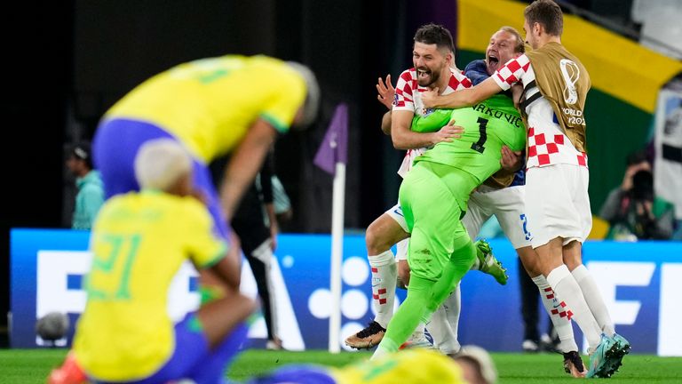 Croatia players embrace goalkeeper Dominik Livakovic as Brazil players show their dejection