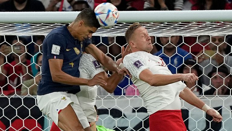 Raphael Varane wins a header in the Poland penalty area