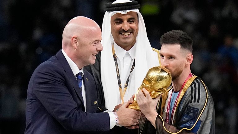 Argentina's Lionel Messi receives the trophy from FIFA President Gianni Infantino, left, and the Emir of Qatar Sheikh Tamim bin Hamad Al Thani, after winning the World Cup final soccer match between Argentina and France at the Lusail Stadium in Lusail, Qatar, Sunday, Dec. 18, 2022. Argentina won 4-2 in a penalty shootout after the match ended tied 3-3. (AP Photo/Martin Meissner)