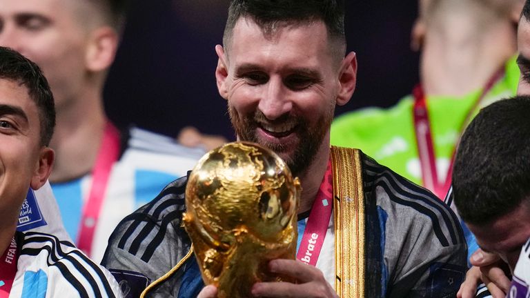 Argentina's Lionel Messi holds the trophy in a Qatari robe after winning the World Cup final