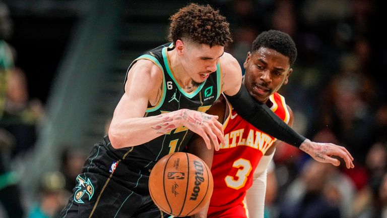 Charlotte Hornets guard LaMelo Ball, left, dribbles under pressure from Atlanta Hawks guard Aaron Holiday, right, during the second half of an NBA basketball game Friday, Dec. 16, 2022, in Charlotte, N.C.