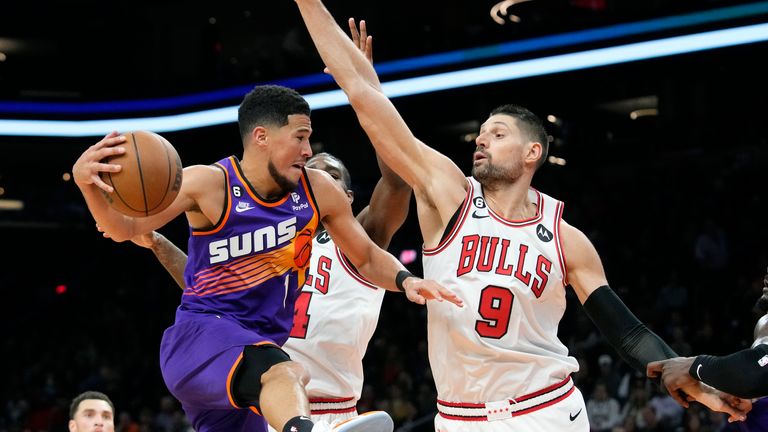 Phoenix Suns guard Devin Booker (1) is stopped on a drive to the basket by Chicago Bulls center Nikola Vucevic (9) and Bulls forward Patrick Williams, second from right, as Bulls guard Zach LaVine, left, looks on during the first half of an NBA basketball game in Phoenix, Wednesday, Nov. 30, 2022