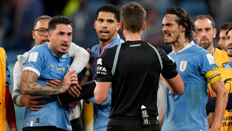 Uruguay players surround referee Daniel Siebert at full time