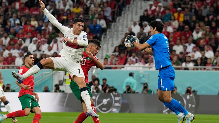 Morocco goalkeeper Yassine Bounou keeps hold of the ball under pressure from Cristiano Ronaldo