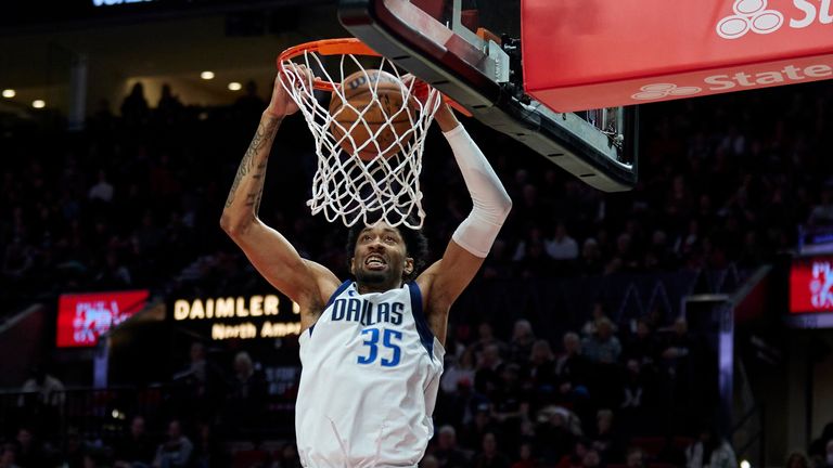 Dallas Mavericks forward Christian Wood, top center, dunks in front of Portland Trail Blazers guard Anfernee Simons, right, and forward Jerami Grant during the first half of an NBA basketball game.