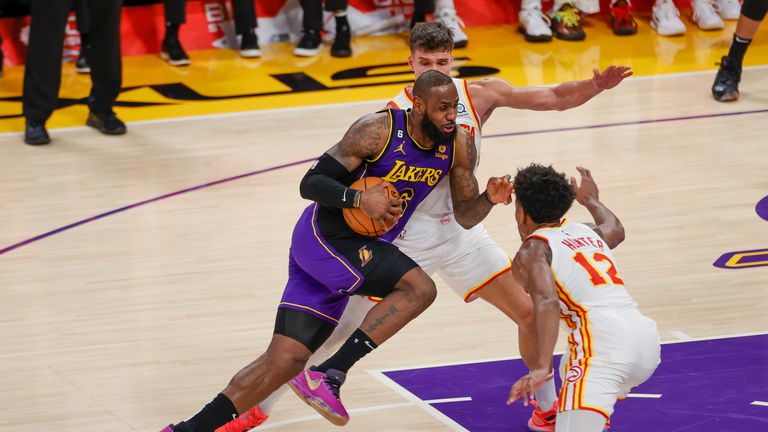Los Angeles Lakers forward LeBron James drives between Atlanta Hawks guard Bogdan Bogdanovic and forward De&#39;Andre Hunter 