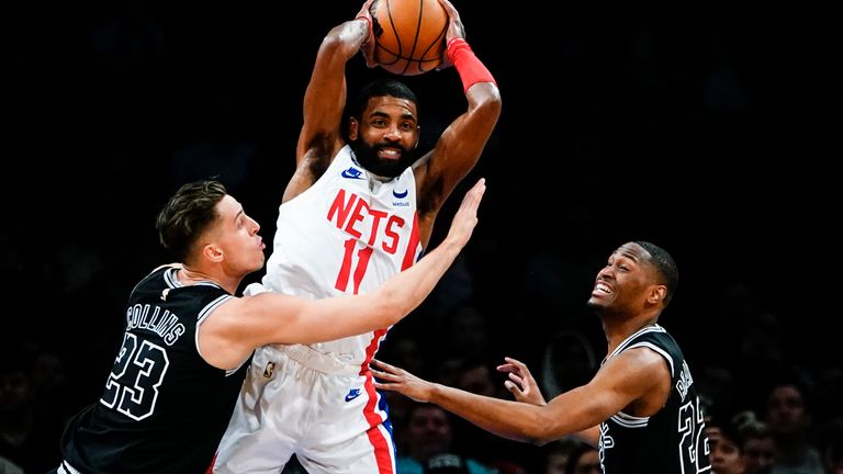 Brooklyn Nets' Kyrie Irving (11) passes away from San Antonio Spurs' Zach Collins and Malaki Branham during the first half of an NBA basketball game, Monday, Jan. 2, 2023, in New York.