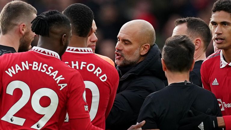 Pep Guardiola is surrounded by Manchester United players as he confronts referee Stuart Attwell at full-time