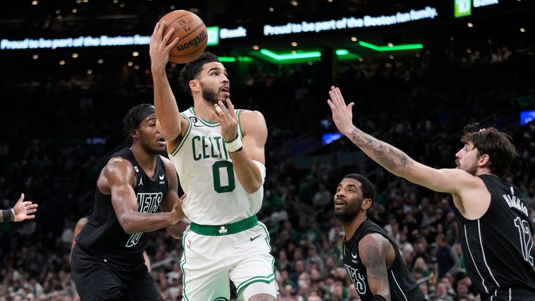 Boston Celtics forward Jayson Tatum tosses up a pass while surrounded by the Brooklyn Nets