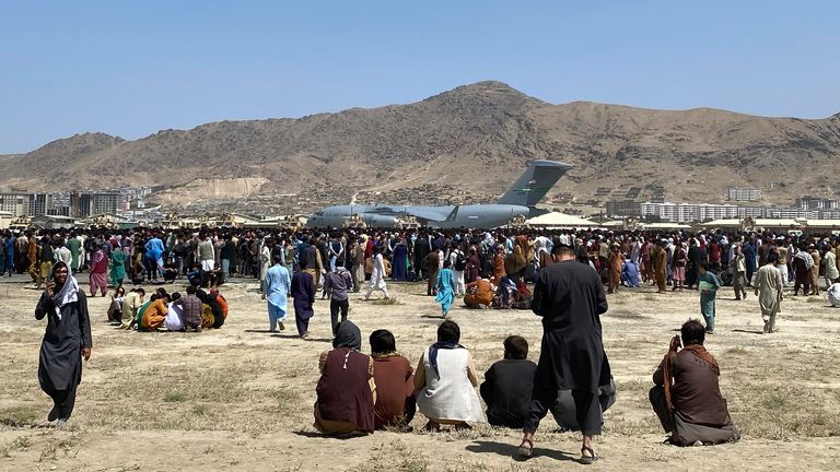 FILE - Hundreds of people gather near a U.S. Air Force C-17 transport plane at the perimeter of the international airport in Kabul, Afghanistan, Aug. 16, 2021. More than a year after the Taliban takeover that saw thousands of Afghans rushing to Kabul's international airport amid the chaotic U.S. withdrawal, Afghans at risk who failed to get on evacuation flights say they are still struggling to find safe and legal ways out of the country. (AP Photo/Shekib Rahmani, File)