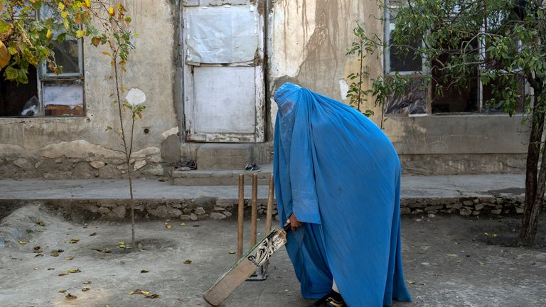 An Afghan woman poses for a photo with her cricket bat in Kabul, Afghanistan, Friday, Nov. 11, 2022. The ruling Taliban have banned women from sports as well as barring them from most schooling and many realms of work. A number of women posed for an AP photographer for portraits with the equipment of the sports they loved. Though they do not necessarily wear the burqa in regular life, they chose to hide their identities with their burqas because they fear Taliban reprisals and because some of them continue to practice their sports in secret. (AP Photo/Ebrahim Noroozi)