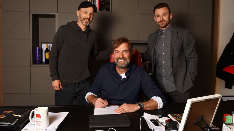 Jurgen Klopp signs a new Liverpool contract flanked by Mike Gordon and Julian Ward