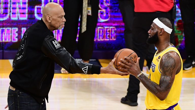 Kareem Abdul-Jabbar hands LeBron James a basketball to mark James breaking Abdul-Jabbar's all-time points record