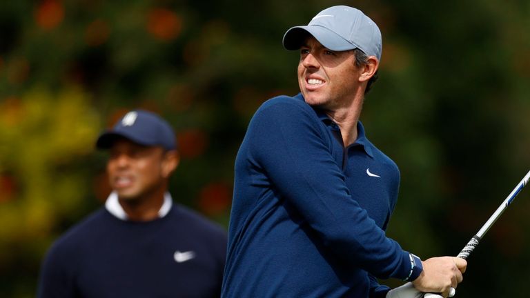 Rory McIlroy hits from the fourth tee as Tiger Woods watches 
