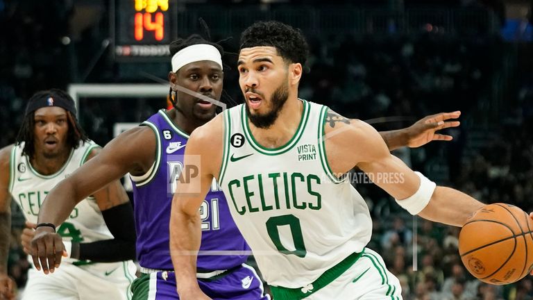 Boston Celtics' Jayson Tatum (0) drives to the basket against Milwaukee Bucks' Jrue Holiday.