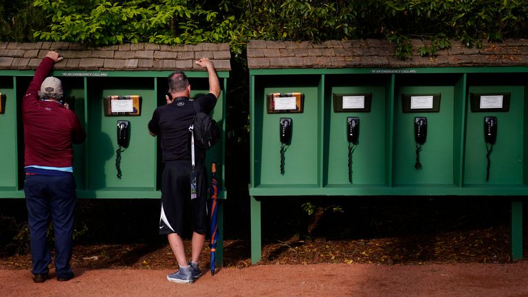 With mobile phone prohibited on the Augusta National Golf Course, spectators use phones provided by the club near the seventh hole during a practice round for the Masters golf tournament on Tuesday, April 5, 2022, in Augusta, Ga. (AP Photo/Jae C. Hong)