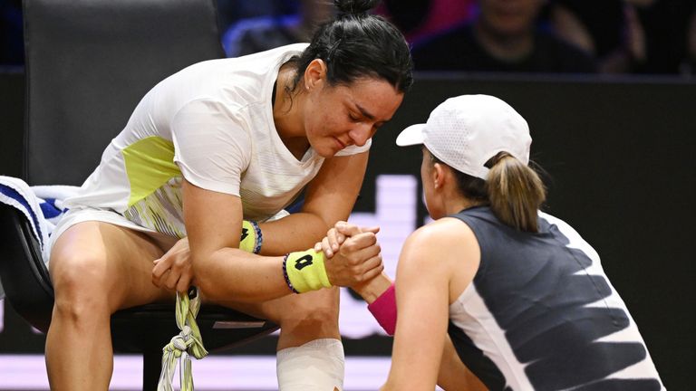A tearful Ons Jabeur (left) is comforted by Iga Swiatek after her injury retirement in their semi-final