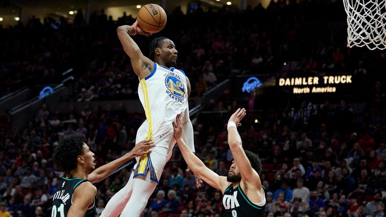 Golden State Warriors forward Jonathan Kuminga, center, dunks over Portland Trail Blazers forward John Butler Jr., left, and guard Skylar Mays during the second half of an NBA basketball game in Portland, Ore., Sunday, April 9, 2023. (AP Photo/Craig Mitchelldyer)