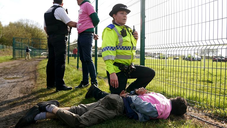 A protester, wearing a pink t-shirt of the Animal Rising group, is stopped by police at Aintree