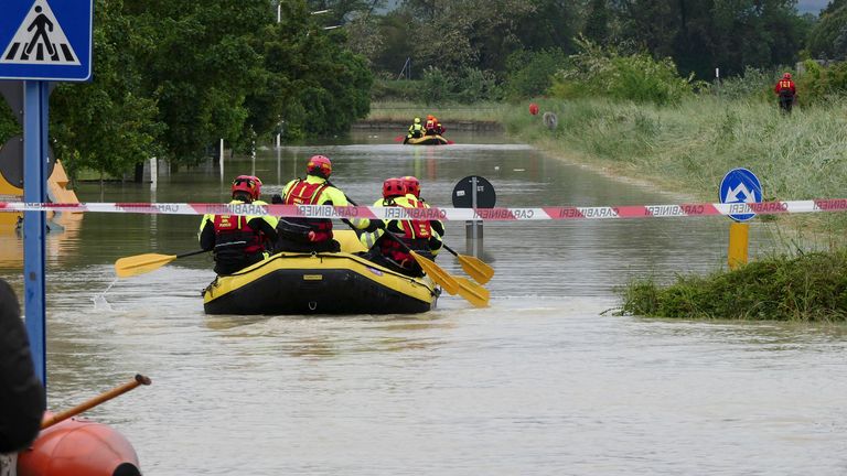 Firefighters use dinghies to cross a flooded road near Faenza in the Emilia-Romagna region of Italy
