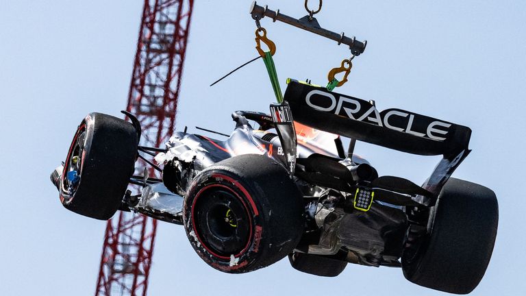 Sergio Perez's damaged Red Bull is lifted off the track