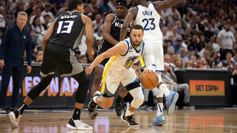 Golden State Warriors guard Stephen Curry  fights through a screen set by teammate Draymond Green as Sacramento Kings forward Keegan Murray pursues 