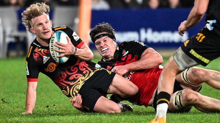 Damian McKenzie, left, of the Chiefs tackled by Scott Barrett of the Crusaders during the Super Rugby Pacific final 