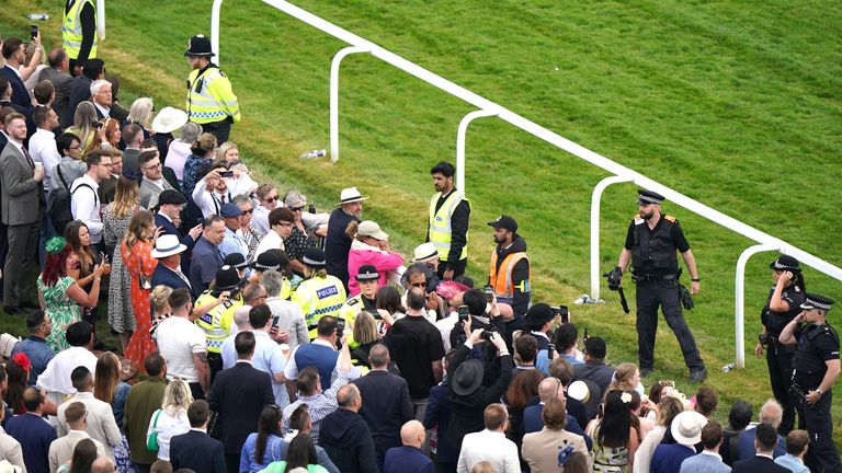 Police detain a protestor at Epsom before the Betfred Derby