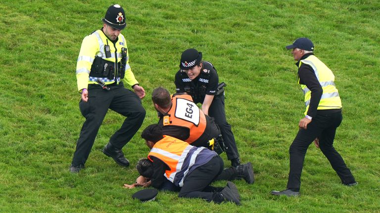 A protestor is detained by police after getting onto the track at Epsom ahead of the Betfred Derby
