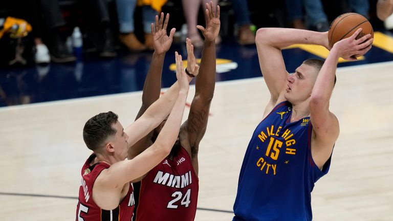 Denver Nuggets center Nikola Jokic, right, shoots over Miami Heat forwards Duncan Robinson, left, and Haywood Highsmith during the first half of Game 1 of basketball's NBA Finals, Thursday, June 1, 2023, in Denver. (AP Photo/David Zalubowski)