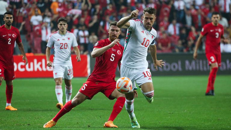 Salih Ozcan dari Turki, kiri, berebut bola dengan pemain Wales.  Harun Ramsey