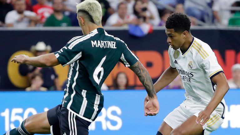 Real Madrid midfielder Jude Bellingham, right, chips the ball over Manchester United defender Lisandro Martinez (6) for a goal during the first half of a Champions Tour friendly soccer match, Wednesday, July 26, 2023, in Houston. (AP Photo/Michael Wyke)