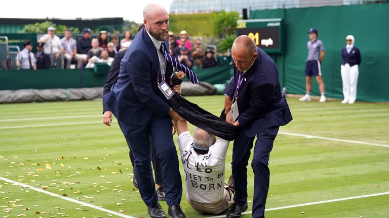 A Just Stop Oil protester is carried off court 18 after throwing confetti on to the grass during Katie Boulter's first-round match against Daria Saville on day three of the 2023 Wimbledon Championships at the All England Lawn Tennis and Croquet Club in Wimbledon.…