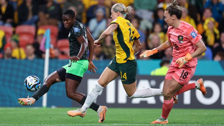 Nigeria's Asisat Oshoala, left, makes a shot on goal for a score to put Nigeria up, 3-1, in front of Australia's Alanna Kennedy, center, and Australia's goalkeeper Mackenzie Arnold during the Women's World Cup Group B soccer match between Australia and Nigeria in Brisbane, Australia, Thursday, July 27, 2023. (AP Photo/Katie Tucker)