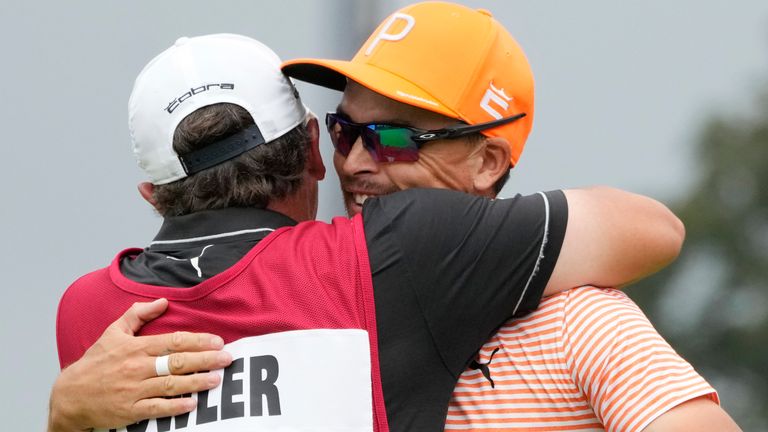 Rickie Fowler is hugged by his caddie Ricky Romano after Fowler's win on the first play-off hole on the 18th green during the final round of the Rocket Mortgage Classic golf tournament at Detroit Country Club, Sunday, July 2, 2023, in Detroit. (AP Photo/Carlos Osorio)