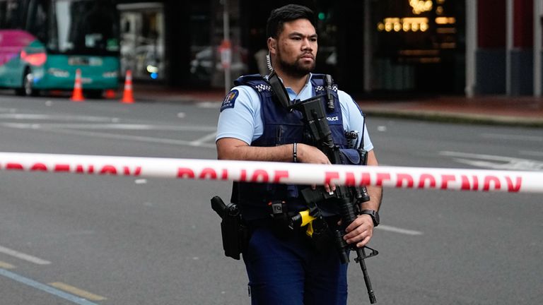 An armed New Zealand police officer stands at a road block in the central business district following a shooting in Auckland, New Zealand