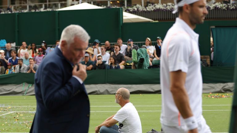 A protester sits on Court 18 after he released confetti in the Championships, Wimbledon